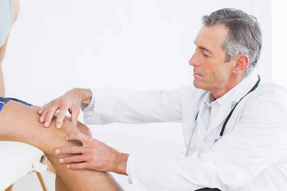 Doctor examining an older patient's knee